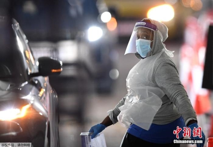 當?shù)貢r間12月18日，英國政府公布的數(shù)據(jù)顯示，當天英國新增奧密克戎毒株感染病例10059例。鑒于奧密克戎毒株感染病例激增，住院人數(shù)不斷上升，倫敦市長宣布倫敦進入“重大事故”狀態(tài)。圖為倫敦的一個免下車檢測中心，一名醫(yī)務工作者正準備對司機進行核酸檢測。