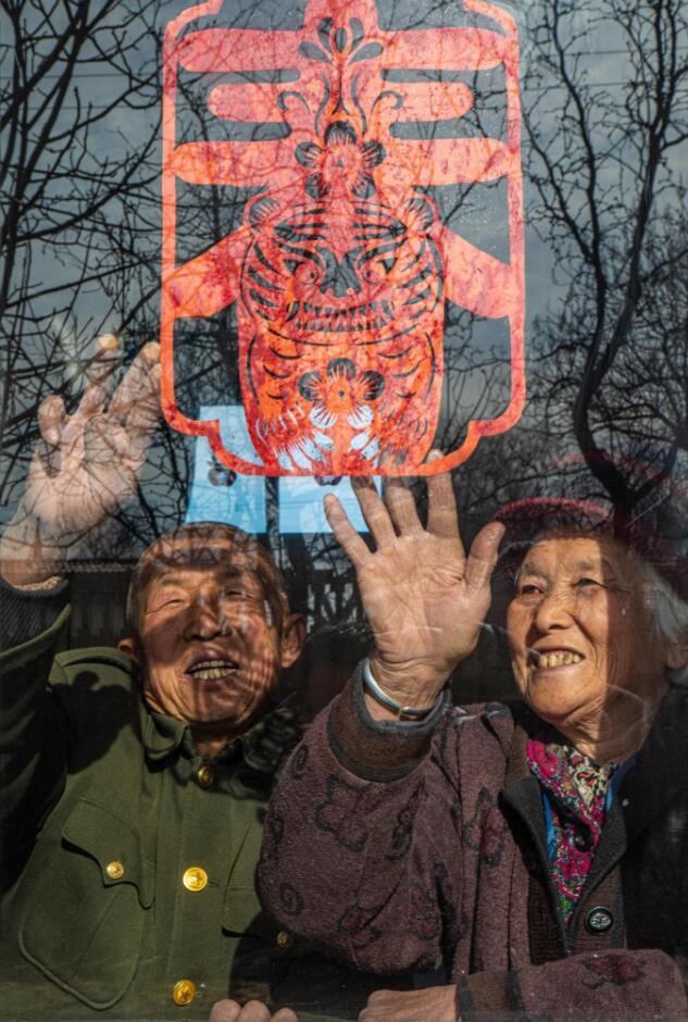 臘月里，霍州市師莊鄉(xiāng)馮南垣村村民師榮光(左)在災(zāi)后重建的新家里貼窗花。(霍州市委宣傳部供圖)