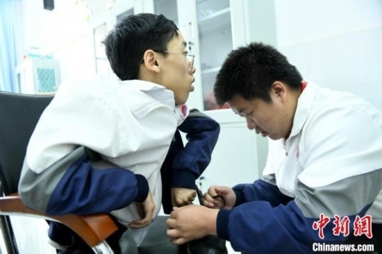 江西省南康中學(xué)北校區(qū)的高三學(xué)生朱金祥(右)正在給鐘華強(qiáng)(左)系好鞋帶。 卓忠偉 攝