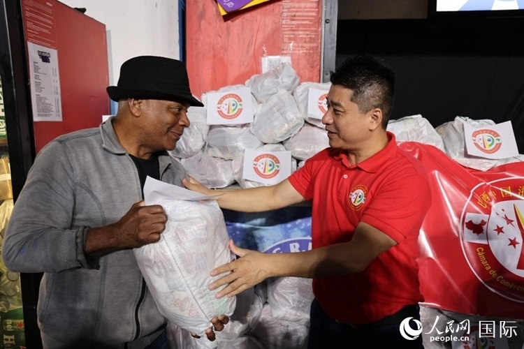 巴西中國浙江商會會長鄭俠茂向社區(qū)居民轉(zhuǎn)交捐贈物資。人民網(wǎng)記者 時元皓攝