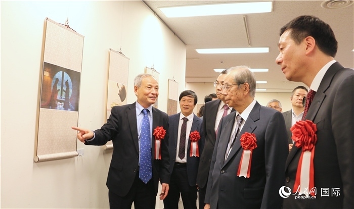 “湖州印象”攝影展主創(chuàng)、世界華人攝影協(xié)會(huì)副會(huì)長(zhǎng)馮學(xué)敏向吳江浩大使、福田康夫前首相等嘉賓介紹展出作品。（人民網(wǎng) 許可攝）