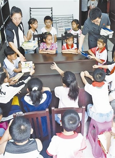  圖④：法院干警為留守兒童發(fā)放暑假讀物。