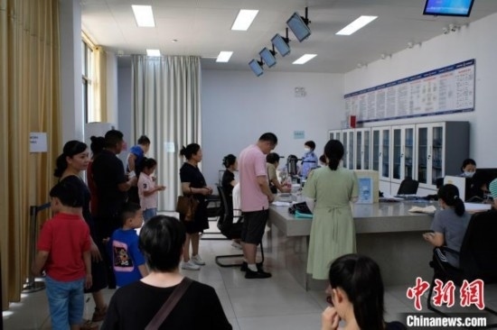 圖為在戶(hù)籍辦證廳內(nèi)排隊(duì)等待的家長(zhǎng)和孩子。劉俊聰 攝