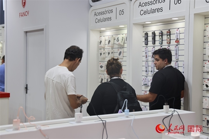 幾名參觀者在一個展臺前了解手機配件。（人民網(wǎng)記者 時元皓攝）