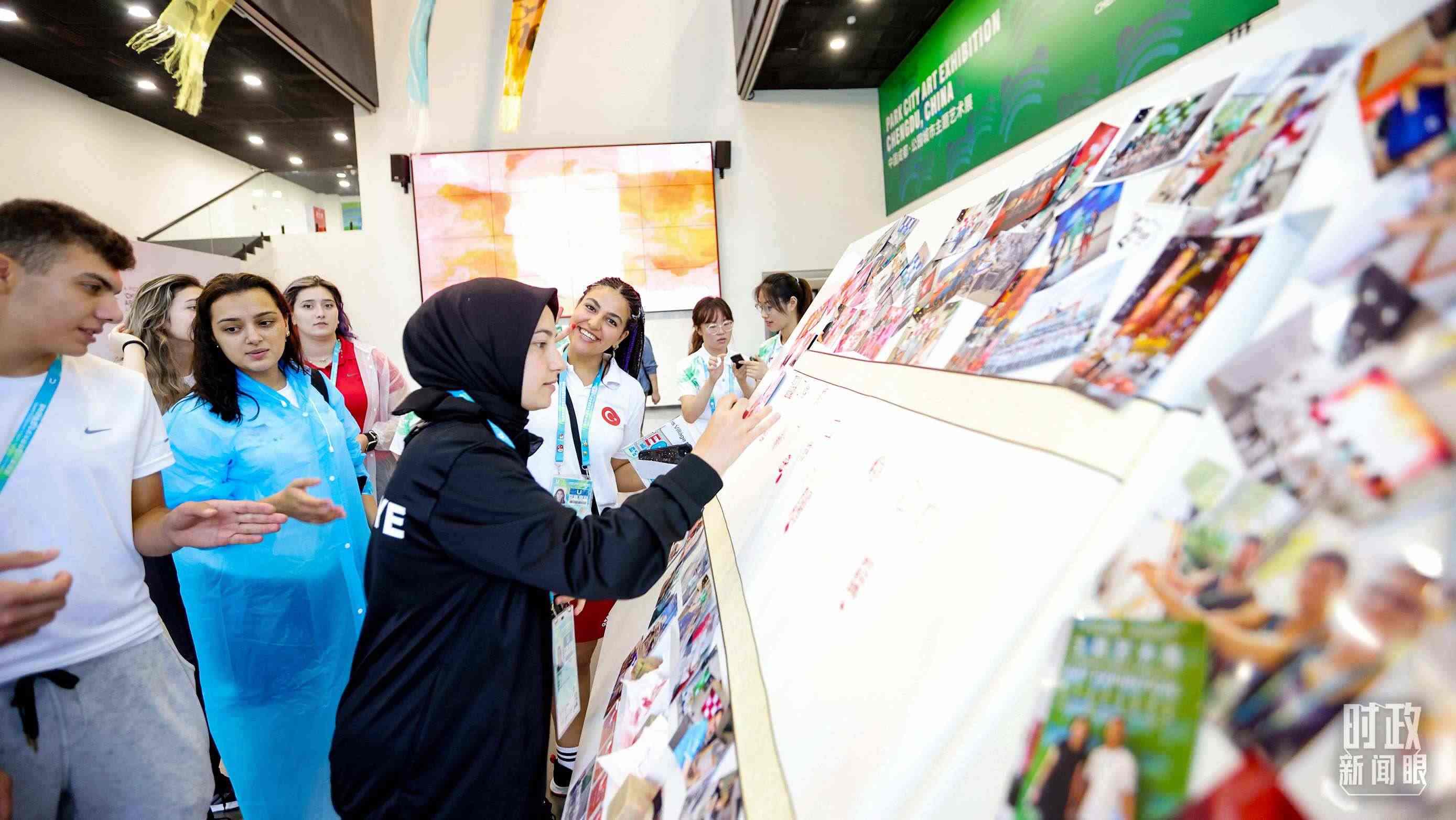 各國青年運(yùn)動(dòng)員正在參觀成都大運(yùn)村內(nèi)的“雪山下的公園城市，煙火里的幸福成都”主題藝術(shù)展。（總臺(tái)央視記者魏幫軍拍攝）