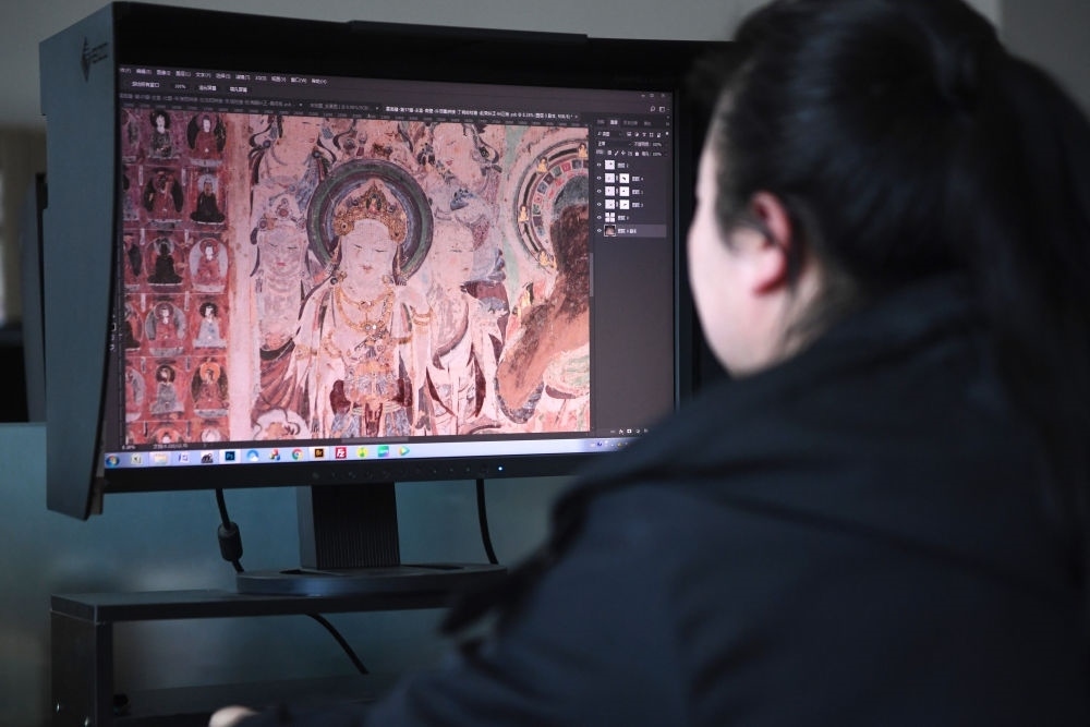 敦煌研究院文物數(shù)字化保護團隊圖像處理人員年海麗在拼接壁畫圖像（2023年4月25日攝）。數(shù)字化探索為莫高窟的保護與傳承開辟了全新路徑，數(shù)字技術(shù)讓敦煌文物走出洞窟，跨出國門，走向“永久保存、永續(xù)利用”。新華社記者 陳斌 攝
