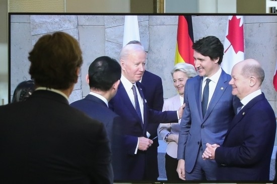 2022年3月24日，在比利時布魯塞爾的北約總部，一名男子觀看屏幕上美國總統(tǒng)拜登（右四）、歐盟委員會主席馮德萊恩（右三）、加拿大總理特魯多（右二）、德國總理朔爾茨（右一）出席七國集團峰會合影儀式的畫面。新華社記者鄭煥松攝