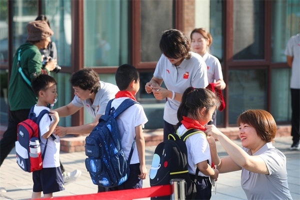 8月30日，雄安史家胡同小學(xué)學(xué)生體驗(yàn)學(xué)校生活。老師為學(xué)生佩戴?；?。