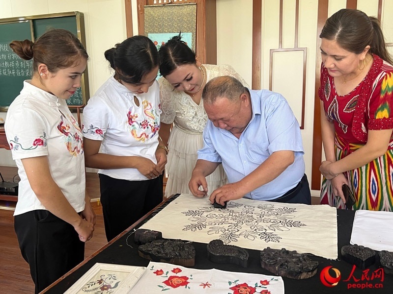 國(guó)家級(jí)非物質(zhì)文化遺產(chǎn)模戳印花布技藝傳承人吾吉阿西木?吾舒爾展示模戳印花布的制作過(guò)程。人民網(wǎng)記者 常雪梅攝