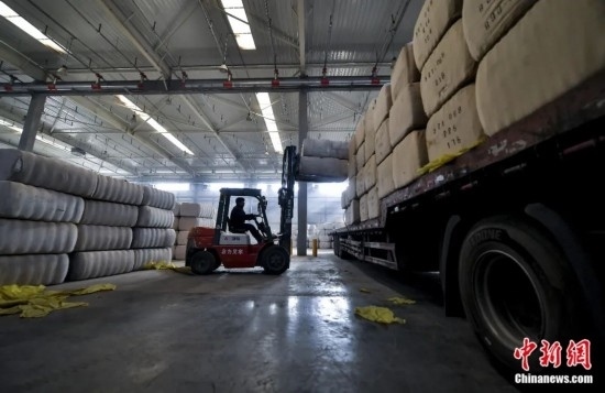 新疆喀什綜合保稅區(qū)，喀什啟路國(guó)際貿(mào)易有限公司的倉(cāng)庫(kù)內(nèi)，工人正在裝載從塔吉克斯坦和烏茲別克斯坦進(jìn)口的棉花。劉新攝