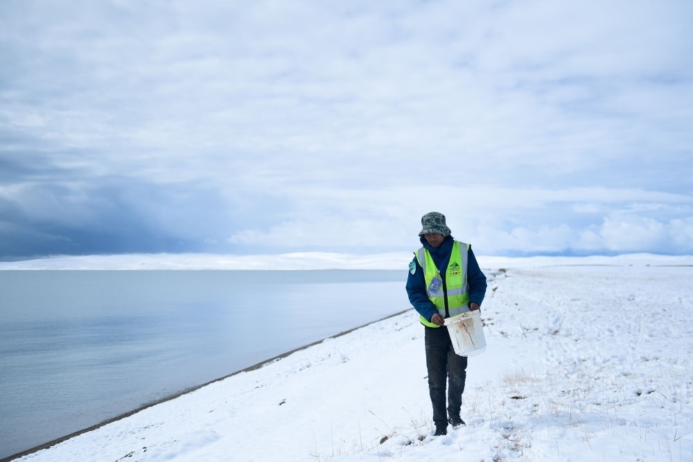 2021年10月20日，在青海省果洛藏族自治州瑪多縣扎陵湖鄉(xiāng)勒那村，三江源國家公園黃河源園區(qū)生態(tài)管護員在扎陵湖邊撿拾垃圾。新華社記者 張龍 攝