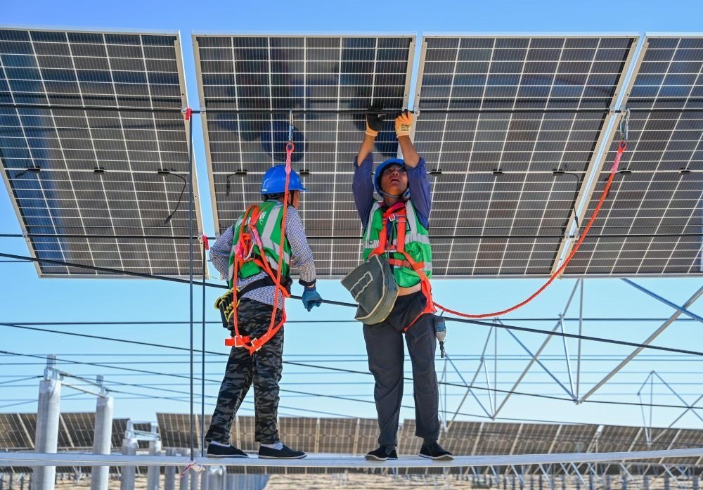 2023年7月22日，工人在位于內(nèi)蒙古杭錦旗庫布其沙漠億利生態(tài)示范區(qū)的蒙西基地庫布其200萬千瓦光伏治沙項目工地安裝光伏板。新華社記者 劉磊 攝