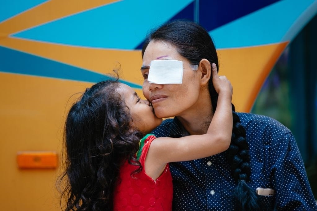 2019年3月15日，在柬埔寨磅湛省醫(yī)院，即將接受白內(nèi)障手術(shù)的患者孫美樂接受女兒的親吻祝福。在接受了中國醫(yī)療隊的白內(nèi)障義診手術(shù)后，她的視力逐步恢復(fù)，生活有了新的光明和希望。