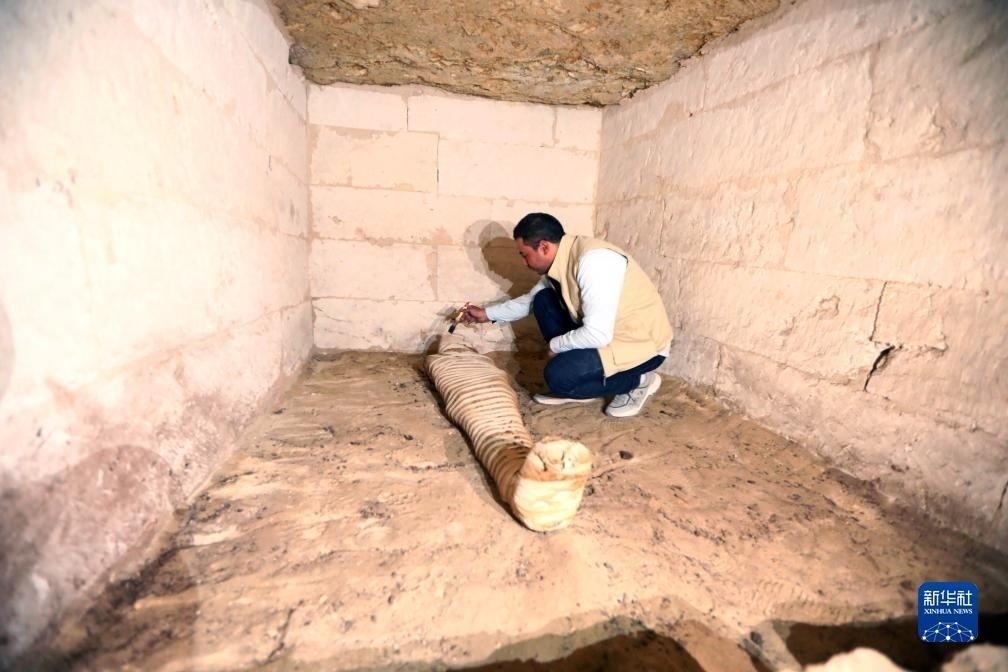 10月15日，在埃及明亞省考古現(xiàn)場(chǎng)，考古人員清理一座石鑿墓中的木乃伊。新華社發(fā)（艾哈邁德·戈馬攝）