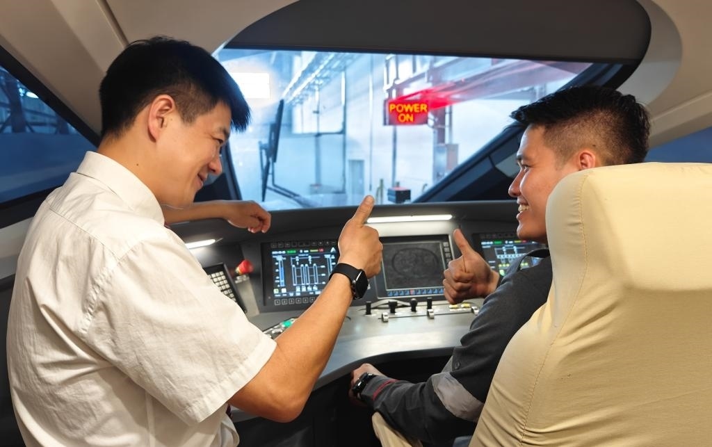 8月25日，在印度尼西亞萬隆的雅萬高鐵德卡魯爾動車所內(nèi)，中國師傅穆振（左）在向印尼火車司機塞蒂亞萬講解動車組出庫前的上電作業(yè)。