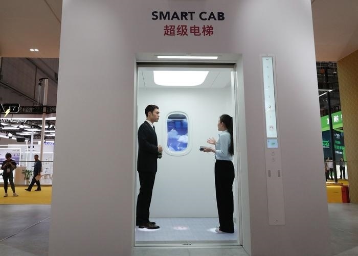 11月5日，工作人員（右）在第六屆進(jìn)博會(huì)上向參觀者介紹奧的斯公司全新推出的超級(jí)電梯。