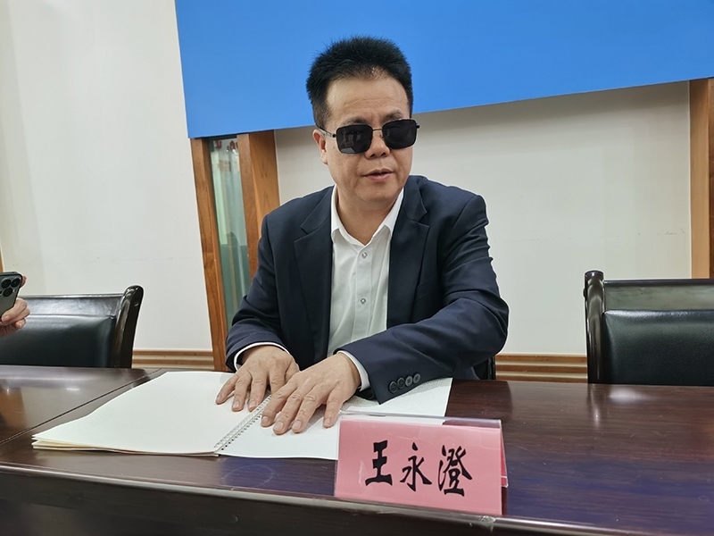 全國人大代表王永澄正在閱讀盲文版代表建議答復(fù)。本報記者 張 璁?dāng)z