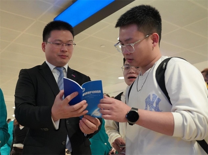 工作人員（左一）在發(fā)放《中國(guó)領(lǐng)事保護(hù)與協(xié)助指南》。 中國(guó)駐迪拜總領(lǐng)事館供圖