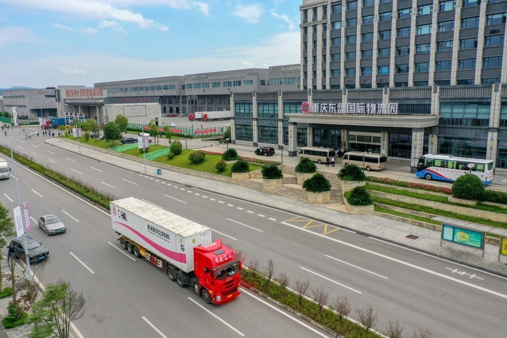 2023年10月11日，滿載筆記本電腦配件、發(fā)電機(jī)組件等產(chǎn)品的西部陸海新通道跨境公路班車從重慶南彭公路保稅物流中心駛出，將途經(jīng)廣西憑祥，直達(dá)越南（無人機(jī)照片）。新華社記者 黃偉 攝