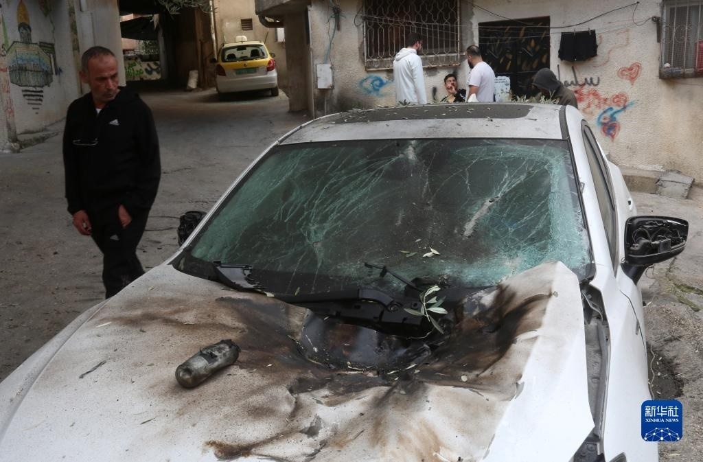 12月17日，在約旦河西岸城市圖勒凱爾姆附近的一處難民營，人們查看在沖突中損毀的車輛。新華社發(fā)（尼達(dá)爾·艾仕塔耶?dāng)z）