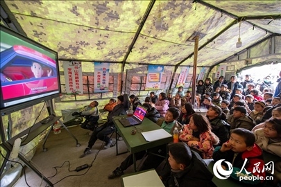 12月22日，在積石山縣大河家鎮(zhèn)大河村安置點(diǎn)，陸軍76集團(tuán)軍某旅搭建的“臨時(shí)學(xué)?！眱?nèi)，小朋友正在看動(dòng)畫片。人民網(wǎng)記者 翁奇羽攝