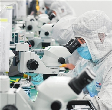 在位于武漢中國(guó)光谷的光電器件研發(fā)制造商——武漢光迅科技股份有限公司生產(chǎn)車(chē)間內(nèi)，技術(shù)人員在光模塊生產(chǎn)線作業(yè)（2023年4月11日攝）。程敏攝/本刊