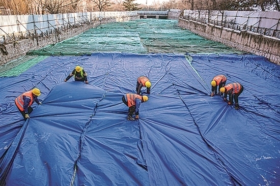 1月3日，房山區(qū)東風(fēng)街道，工人正在修復(fù)的河道內(nèi)給混凝土鋪設(shè)保溫布。