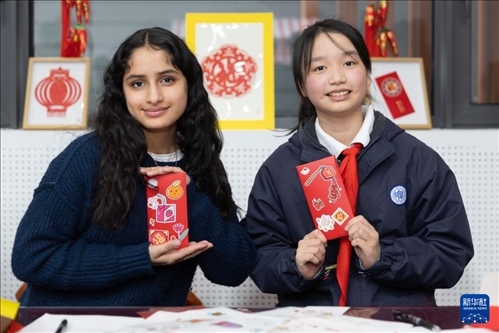 1月28日，美國(guó)馬斯卡廷中學(xué)學(xué)生（左）和復(fù)旦大學(xué)第二附屬學(xué)校學(xué)生展示互相送出的寫(xiě)有寄語(yǔ)祝福的紅包。 新華社記者 王翔 攝