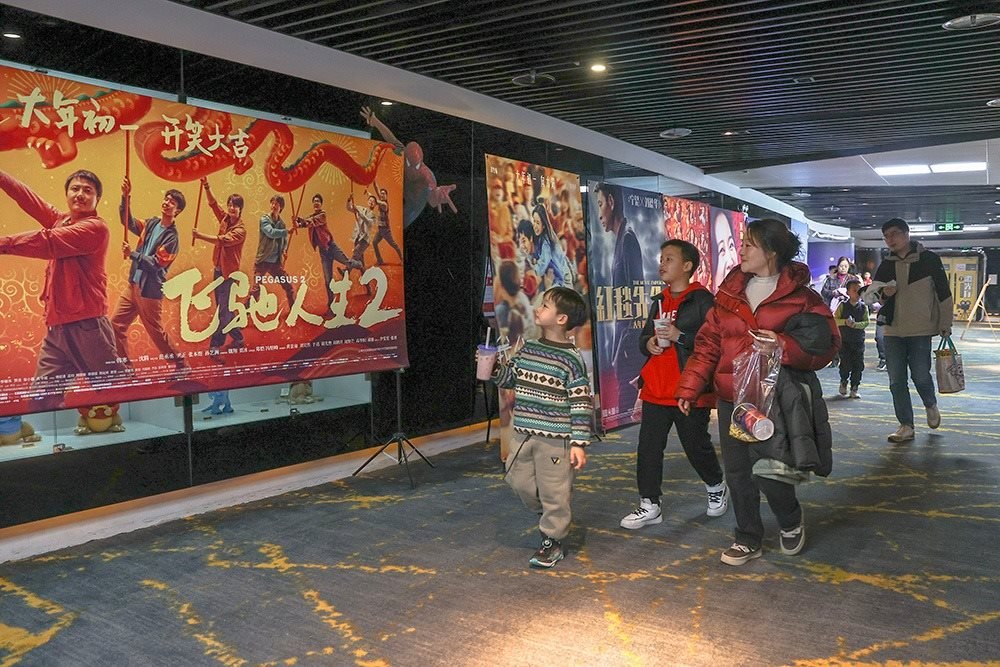 △ 2024年2月16日，在江西贛州一家電影院，觀眾從春節(jié)檔電影的宣傳展板前走過(guò)。