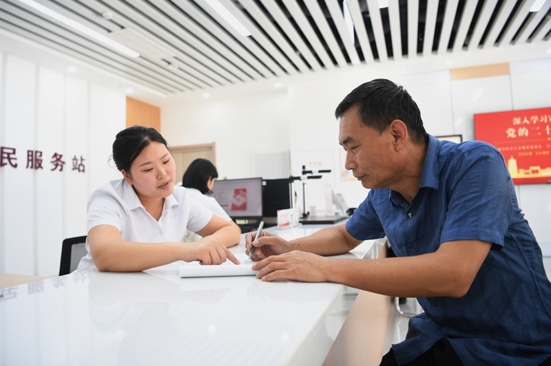 2023年5月23日，河北雄安新區(qū)容東片區(qū)南文營社區(qū)居民（右）在社區(qū)便民服務(wù)站辦理業(yè)務(wù)。
