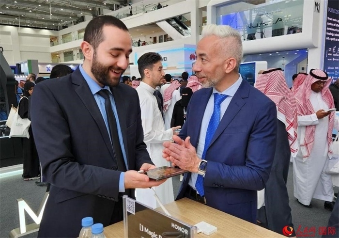 兩名觀眾在榮耀手機展臺前交流。人民網(wǎng)記者 管克江攝