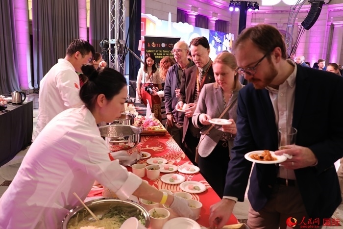 當(dāng)?shù)貢r(shí)間3月7日晚，華盛頓聯(lián)合車站廣場舉行駐美使團(tuán)“使館主廚挑戰(zhàn)賽”。圖為當(dāng)?shù)孛癖娫谥袊古_前體驗(yàn)中國美食。人民網(wǎng)記者 李志偉攝