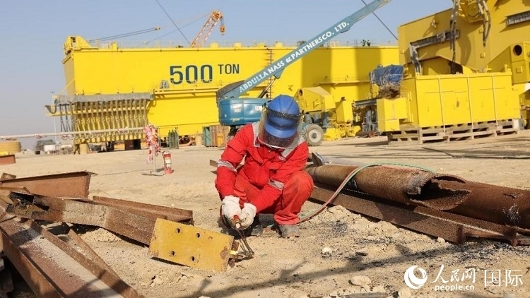 工人正在龍門吊吊裝現(xiàn)場(chǎng)切割金屬件。人民網(wǎng)記者管克江攝