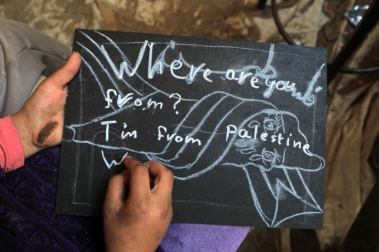 2023年12月28日，一名學(xué)生在加沙地帶南部城市拉法一所學(xué)校的臨時(shí)教室中寫下“我來自巴勒斯坦”的字樣。新華社發(fā)（里澤克·阿卜杜勒賈瓦德攝）