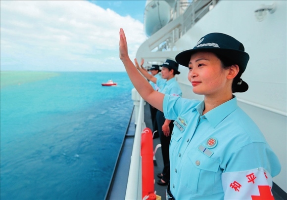 中國(guó)海軍“和平方舟”號(hào)醫(yī)院船結(jié)束訪問湯加時(shí)，任務(wù)官兵中的文職人員向歡送人群揮手告別（2023年8月4日攝）。徐巍攝/本刊