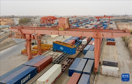 4月21日，二連浩特鐵路口岸龍門吊吊裝中歐班列集裝箱（無人機照片）。 新華社發(fā)（張海峰攝）