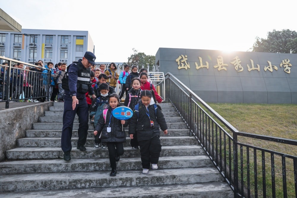 2023年12月20日，秀山派出所民警在秀山小學(xué)放學(xué)時(shí)間參與“護(hù)學(xué)崗”維持秩序，同時(shí)接獨(dú)自放學(xué)的學(xué)生去“民生小鋪”。浙江省舟山市岱山縣公安局秀山派出所聯(lián)合鄉(xiāng)鎮(zhèn)、社區(qū)成立“民生小鋪”，為當(dāng)?shù)鼐用?、外來?wù)工人員及其子女等服務(wù)，協(xié)助解決外來務(wù)工人員在工作、生活等方面的矛盾和問題，助力鄉(xiāng)鎮(zhèn)基層治理。新華社記者 徐昱 攝