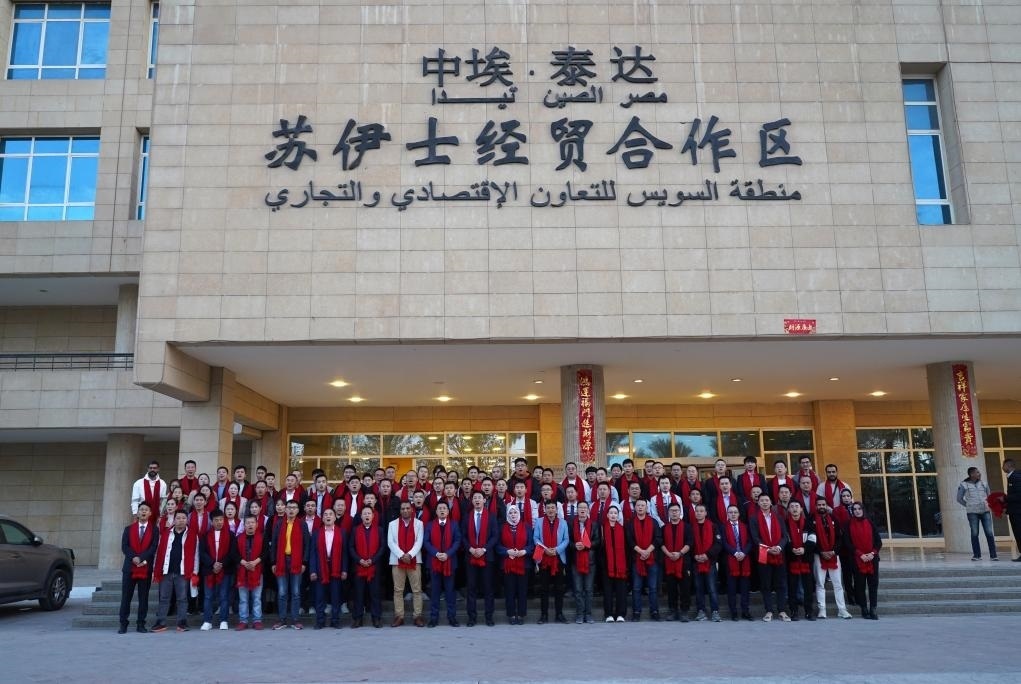 2024年2月11日，在位于埃及蘇伊士省的中?！ぬ┻_(dá)蘇伊士經(jīng)貿(mào)合作區(qū)，中埃員工在合作區(qū)辦公大樓前合影拜年。新華社發(fā)（泰達(dá)合作區(qū)供圖）