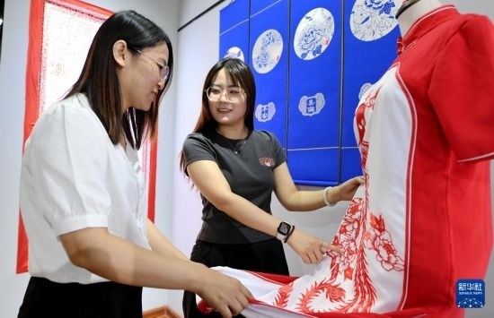 5月31日，在衡水市阜城縣一家剪紙工作室，游客在觀賞帶有剪紙元素的旗袍。