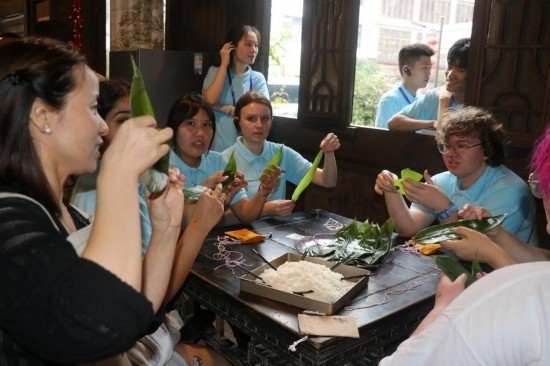 6月9日，美國青年代表在重慶永川松溉古鎮(zhèn)體驗包粽子。新華社記者 周思宇 攝