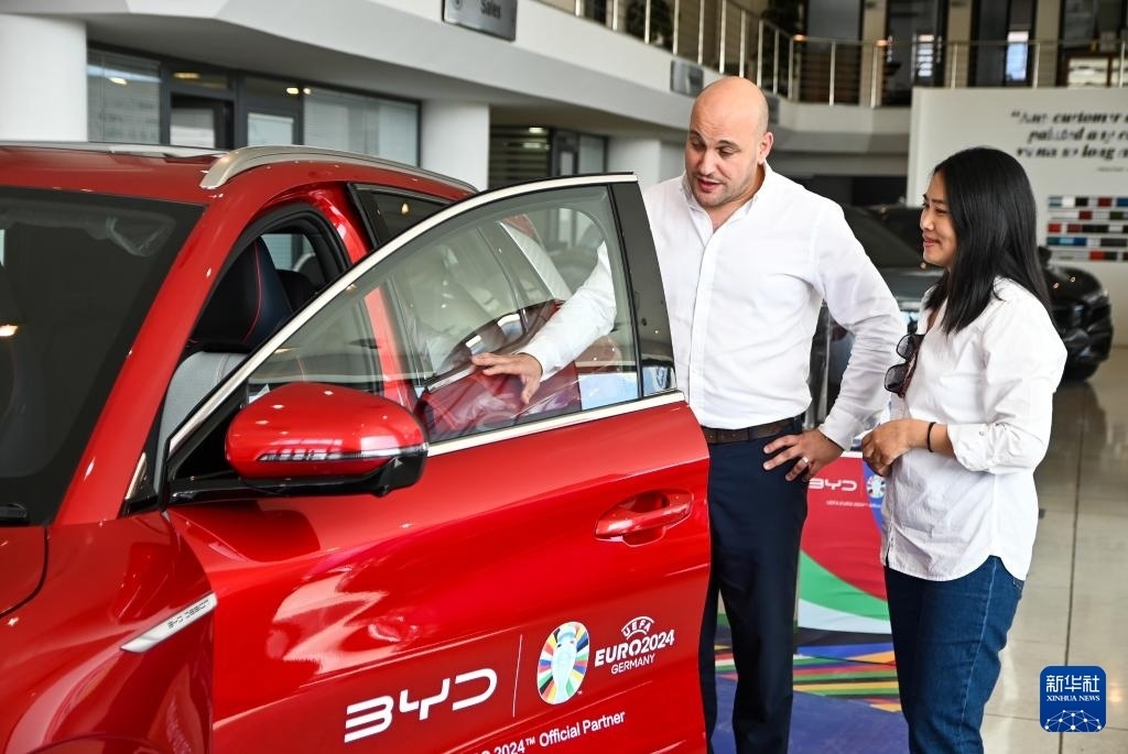 2024年5月29日，在馬耳他比爾基卡拉，馬耳他哈桑-扎米特汽車公司首席執(zhí)行官德古阿拉（左）介紹一輛比亞迪純電動汽車。新華社發(fā)（喬納森·博格 攝）