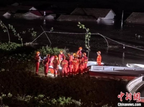  7月6日凌晨3時，在湖南岳陽華容縣團洲垸洞庭湖一線堤防，救援人員剛剛完成一次救援任務，遠處是被淹的民房。中新社記者 白祖偕 攝