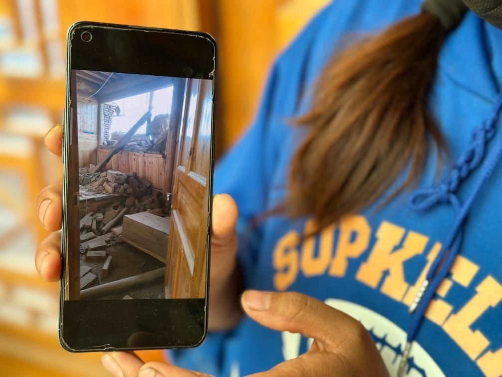 圖為7月17日拉毛東智在手機(jī)上找出地震后房屋受損的照片。新華社記者 張子琪 攝