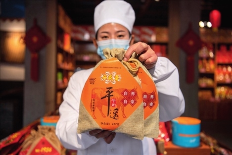 在位于山西省晉中市平遙縣的平遙古城南大街的一家平遙牛肉店內(nèi)，工作人員展示一款牛肉產(chǎn)品（資料照片）楊晨光攝 / 本刊