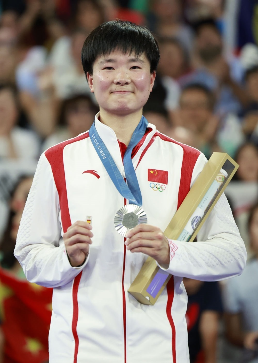 巴黎奧運會羽毛球女子單打亞軍、中國選手何冰嬌在頒獎儀式上一手握著銀牌，一手握著西班牙奧委會徽章（2024年8月5日攝）。新華社記者 任正來 攝