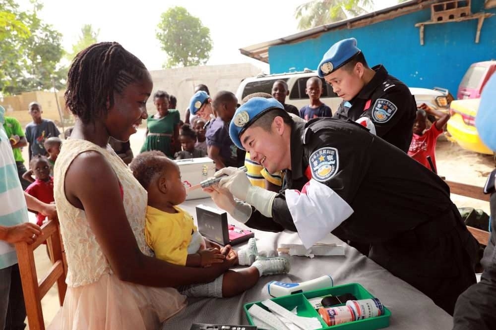 2017年12月28日，在利比里亞蒙羅維亞，中國維和警察防暴隊(duì)醫(yī)療人員為兒童做口腔檢查。