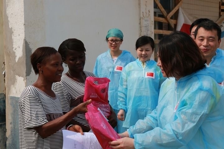2015年4月4日，在位于塞拉利昂首都弗里敦市郊的中塞友好醫(yī)院埃博拉診療中心，中國(guó)第四批援塞醫(yī)療隊(duì)副隊(duì)長(zhǎng)邵蔚（右前）向被治愈的埃博拉出血熱患者贈(zèng)送禮物。新華社發(fā)（祖榮強(qiáng) 攝）