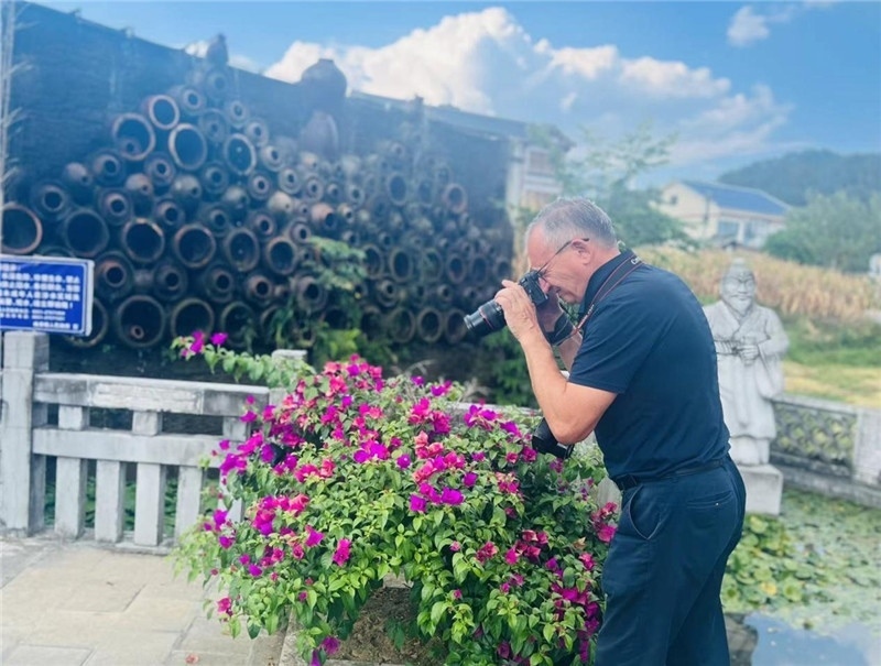 遠(yuǎn)處黔北民居錯落有致，近處一只黑色的蝴蝶穿梭于粉紫色三角梅花叢間隙，與俄羅斯“大歐亞”總編輯弗拉基米爾·別列日內(nèi)赫的鏡頭玩起了捉迷藏，“你追我逃，不亦樂乎”。（張亞欣攝）