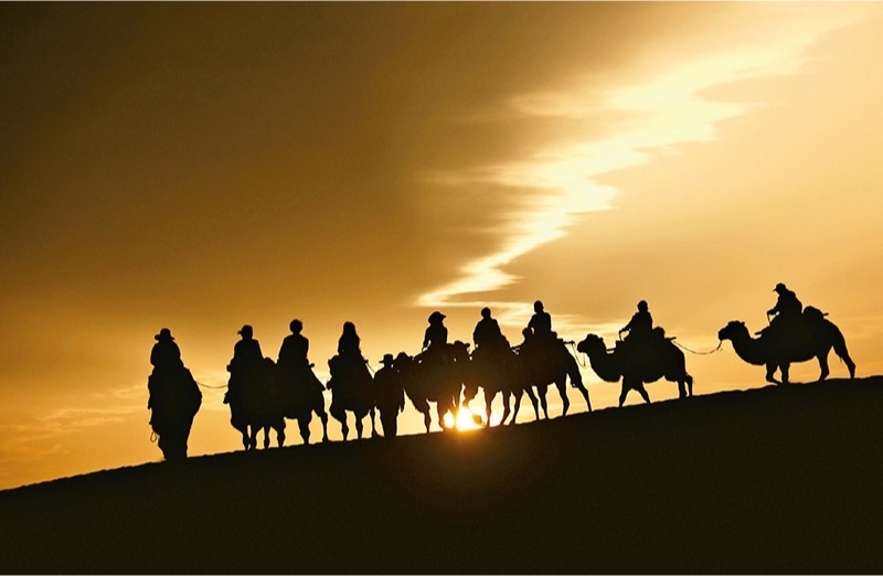 新時代以來，文化和旅游深度融合發(fā)展體制機(jī)制不斷健全，成功走出了一條獨具特色的中國旅游發(fā)展之路。圖為2024年9月1日清晨，游客在甘肅省敦煌市鳴沙山月牙泉景區(qū)乘騎駱駝，欣賞大漠風(fēng)光，體驗絲路風(fēng)情。 新華社發(fā) 張曉亮/攝