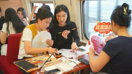 10月1日，旅客們?cè)贕1634次列車上給油紙傘作畫。新華社記者周義 攝
